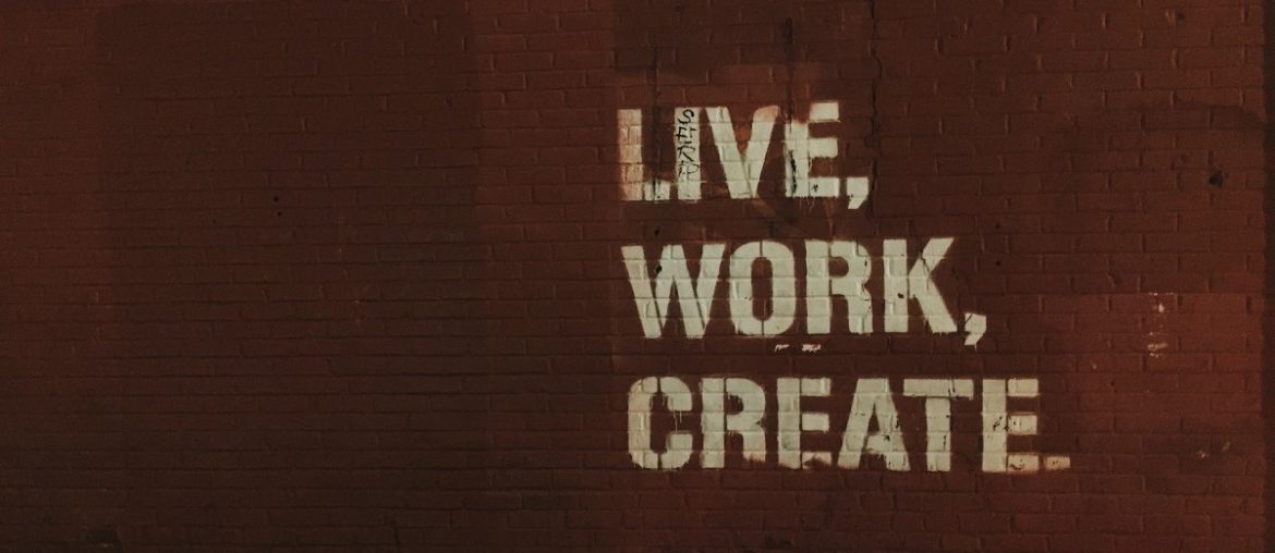 A brick wall with "live, work, create" painted on it