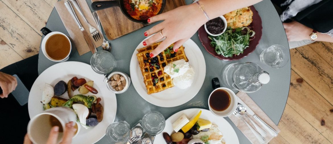 A picture from above featuring breakfast plates (like waffles, eggs, and potatoes) at a dining restaurant.