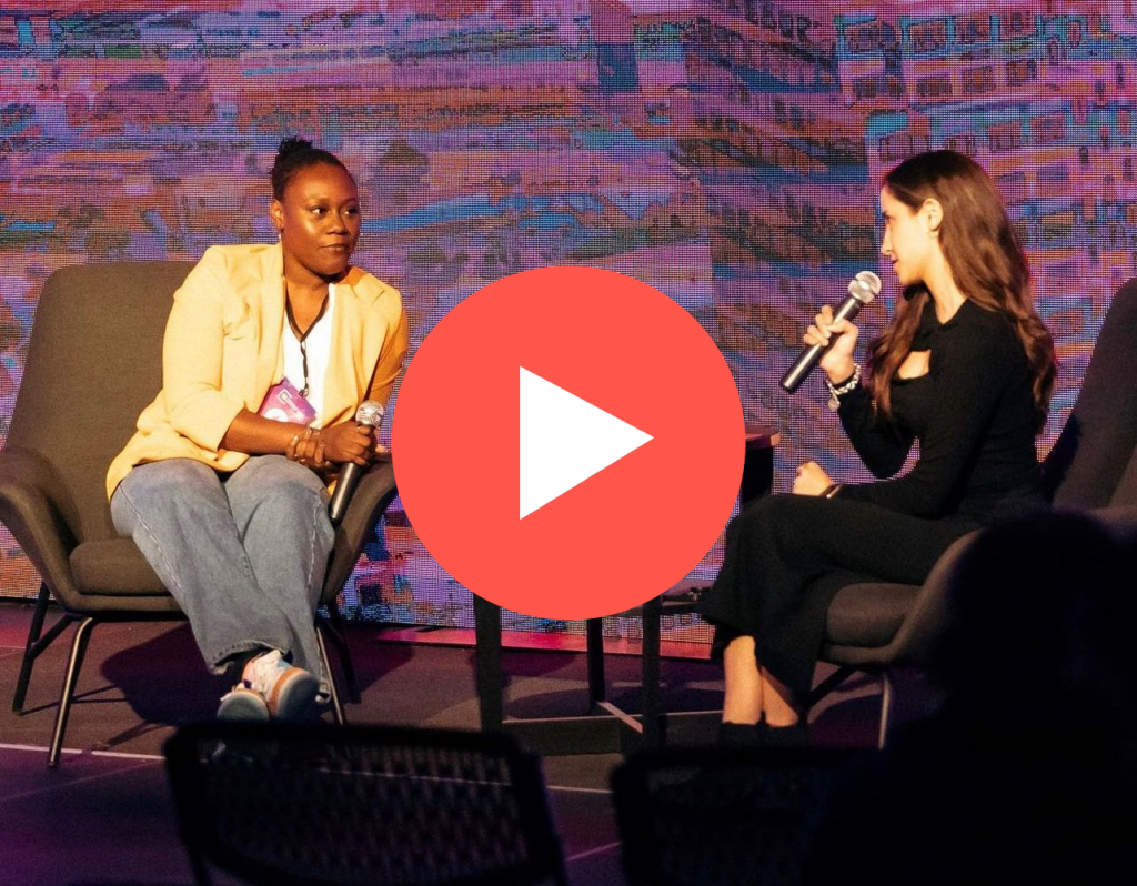 Two women speaking on stage, on a live podcast 
